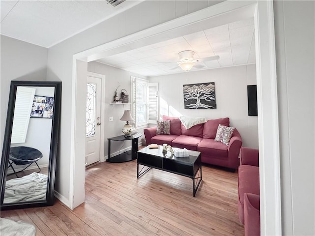 living area with light wood-style flooring, a ceiling fan, and baseboards