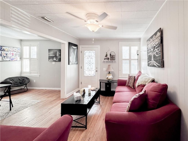 living room with visible vents, light wood-style flooring, baseboards, and a ceiling fan