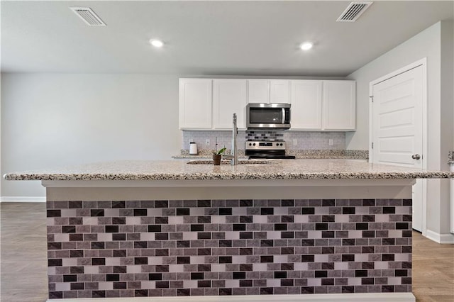 kitchen with white cabinetry, sink, light stone countertops, and appliances with stainless steel finishes