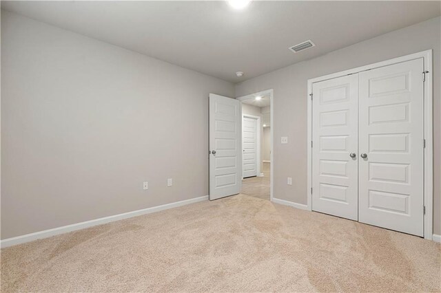 unfurnished bedroom featuring light carpet and a closet