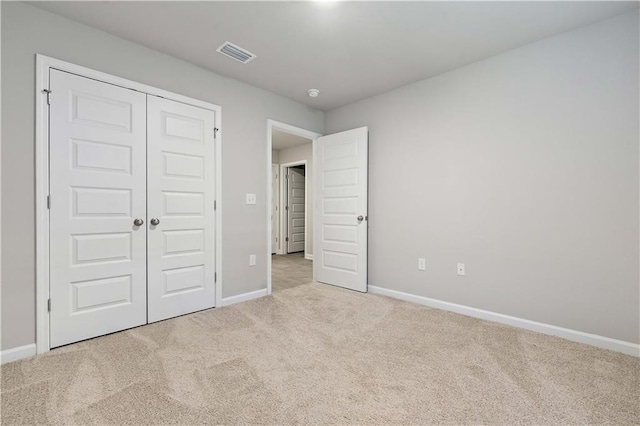 unfurnished bedroom with light carpet and a closet