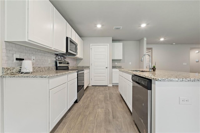 kitchen with light stone countertops, light wood-type flooring, stainless steel appliances, sink, and white cabinetry