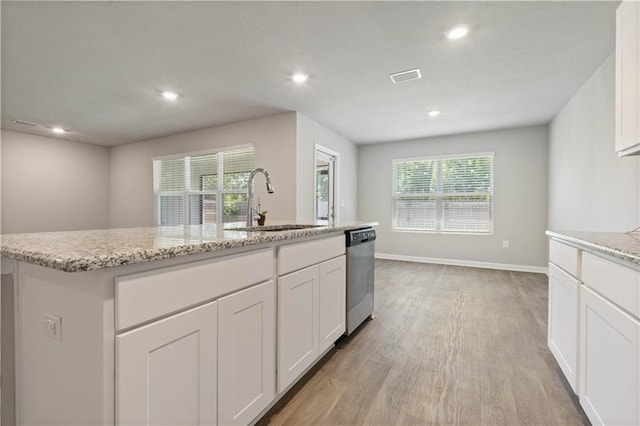 kitchen featuring white cabinets, a center island with sink, sink, stainless steel dishwasher, and light hardwood / wood-style floors