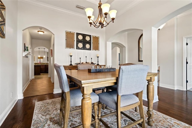 dining room featuring dark hardwood / wood-style flooring, a notable chandelier, and crown molding