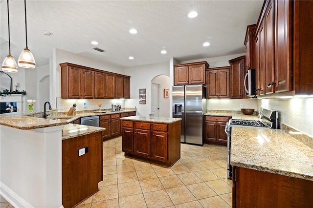 kitchen featuring hanging light fixtures, stainless steel appliances, light stone counters, a kitchen island, and kitchen peninsula