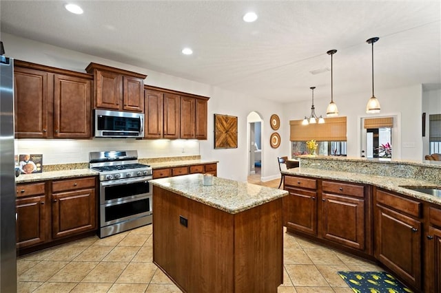 kitchen with light stone counters, a center island, light tile patterned floors, appliances with stainless steel finishes, and pendant lighting