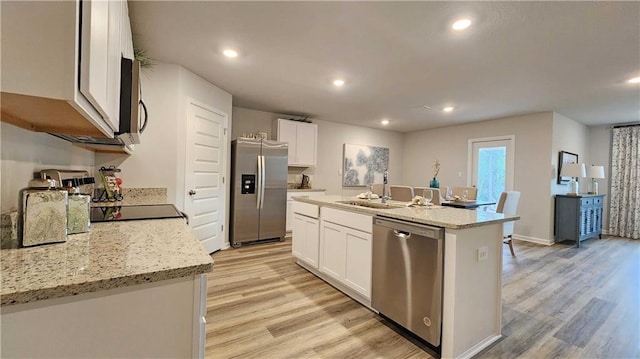 kitchen featuring a kitchen island with sink, stainless steel appliances, white cabinets, and light wood-type flooring