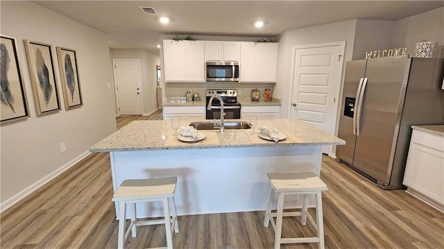 kitchen featuring stainless steel appliances, sink, an island with sink, and a breakfast bar area