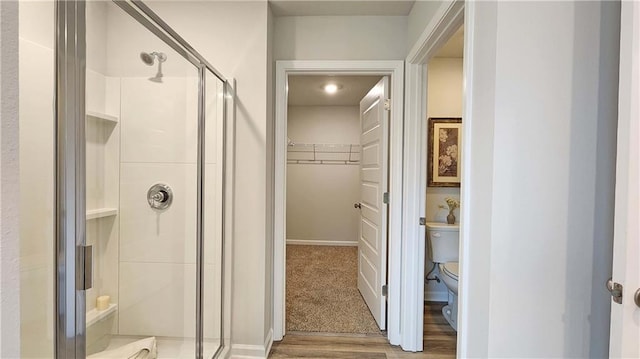 bathroom with walk in shower, toilet, and hardwood / wood-style flooring