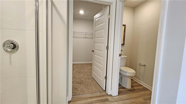 bathroom featuring wood-type flooring, a shower, and toilet