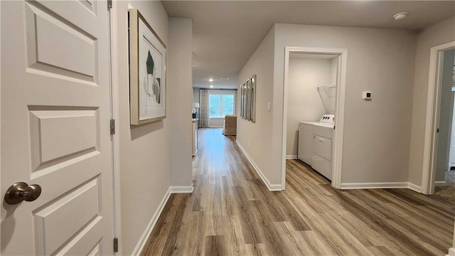 corridor with washer and clothes dryer and light wood-type flooring