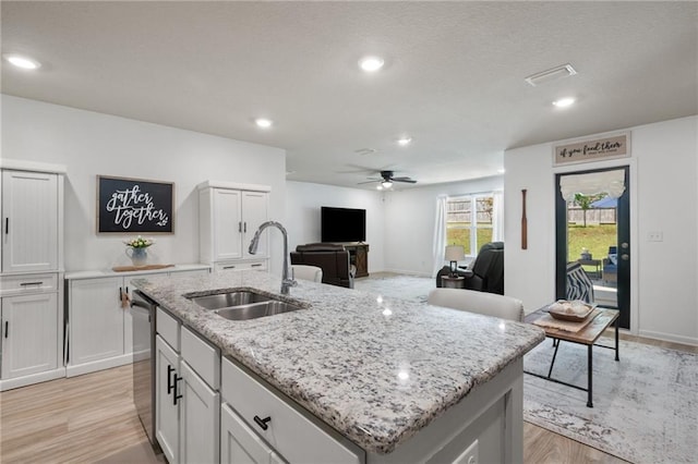 2526 Windmere Dr E, Semmes, AL 36575 - kitchen with a ceiling fan, light stone countertops, light wood-style floors, a center island with sink, and a sink