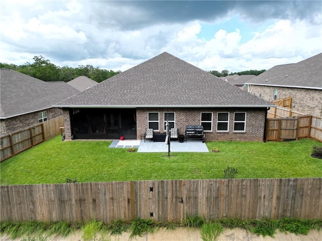 back of house with a fenced backyard, brick siding, a patio area, and a lawn