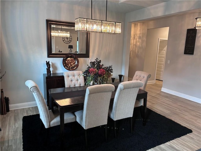 dining space with baseboards, wood finished floors, and an inviting chandelier