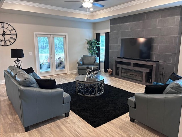 living area featuring plenty of natural light, a ceiling fan, ornamental molding, and light wood-style flooring