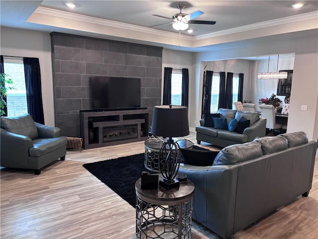living room with plenty of natural light, wood finished floors, ceiling fan, and crown molding