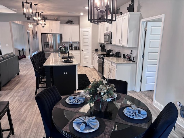 dining room with light wood-type flooring, baseboards, and an inviting chandelier