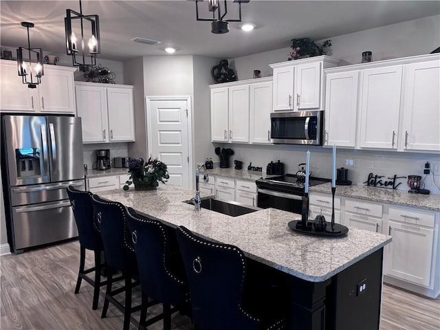 kitchen featuring white cabinets, appliances with stainless steel finishes, a sink, and visible vents
