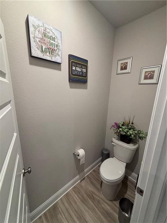 bathroom with baseboards, wood finished floors, and toilet