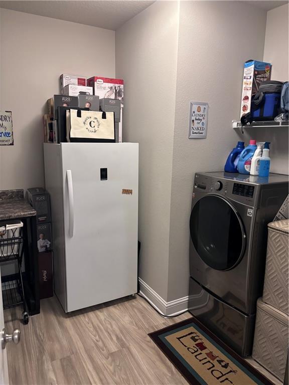 washroom with light wood-style flooring, baseboards, laundry area, and washer / dryer