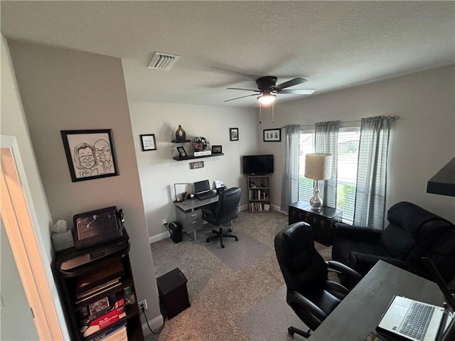 carpeted home office featuring baseboards, visible vents, a textured ceiling, and ceiling fan