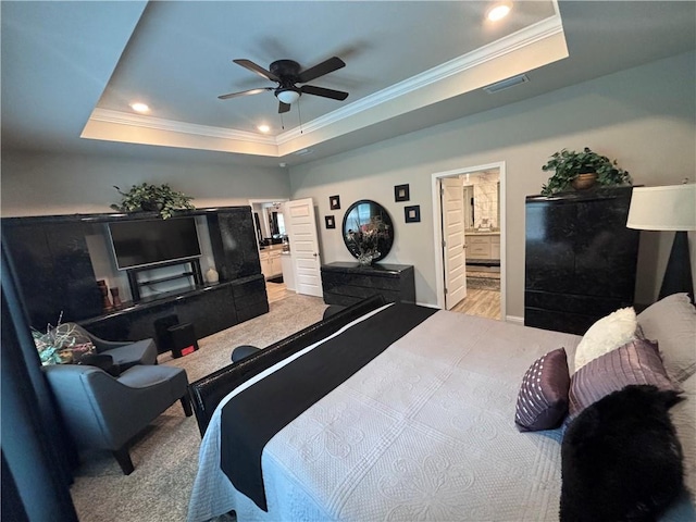 bedroom with ensuite bath, a tray ceiling, recessed lighting, and crown molding