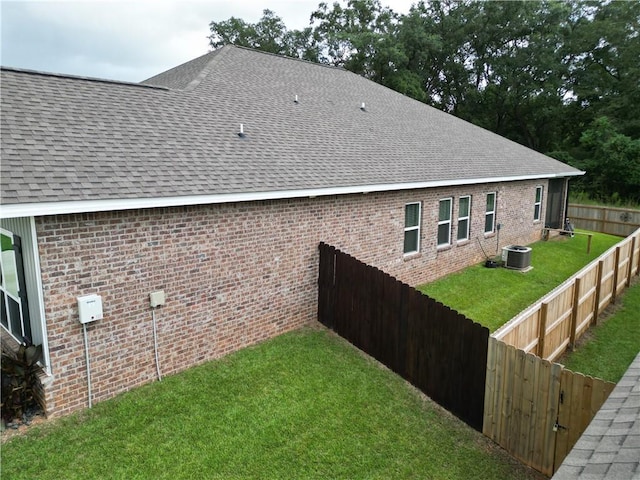 view of home's exterior featuring a fenced backyard, brick siding, a yard, and a shingled roof