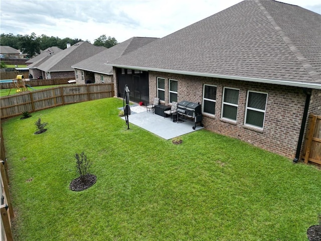 back of house with a shingled roof, a fenced backyard, a patio, a lawn, and brick siding