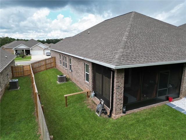 rear view of property featuring brick siding, a sunroom, and a shingled roof