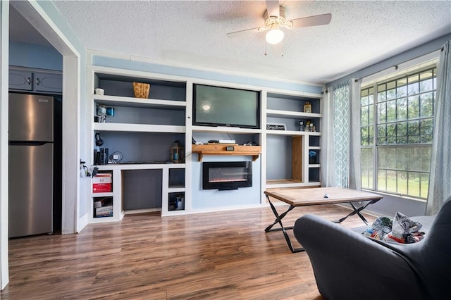 8920A Chunchula-Georgetown Rd, Chunchula, AL 36521 - living room featuring built in features, a glass covered fireplace, wood finished floors, a textured ceiling, and a ceiling fan