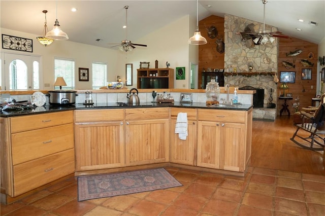 kitchen with ceiling fan, a stone fireplace, sink, vaulted ceiling, and hardwood / wood-style flooring