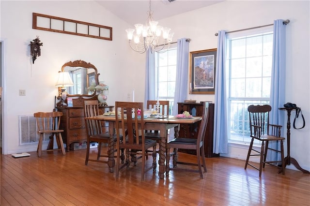 dining room featuring wood-type flooring, vaulted ceiling, and a notable chandelier