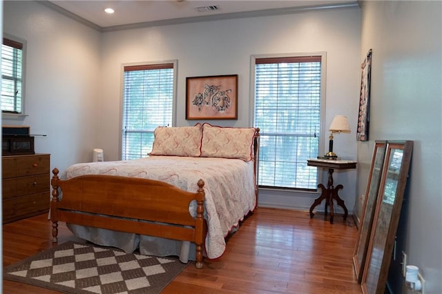 bedroom featuring hardwood / wood-style floors, crown molding, and multiple windows