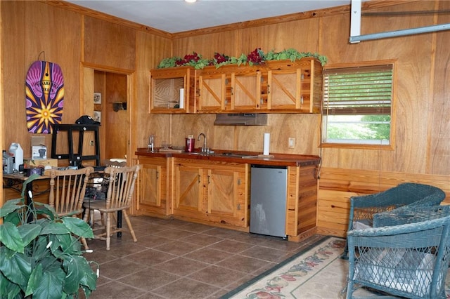 kitchen with sink, dishwasher, wooden walls, and tile floors