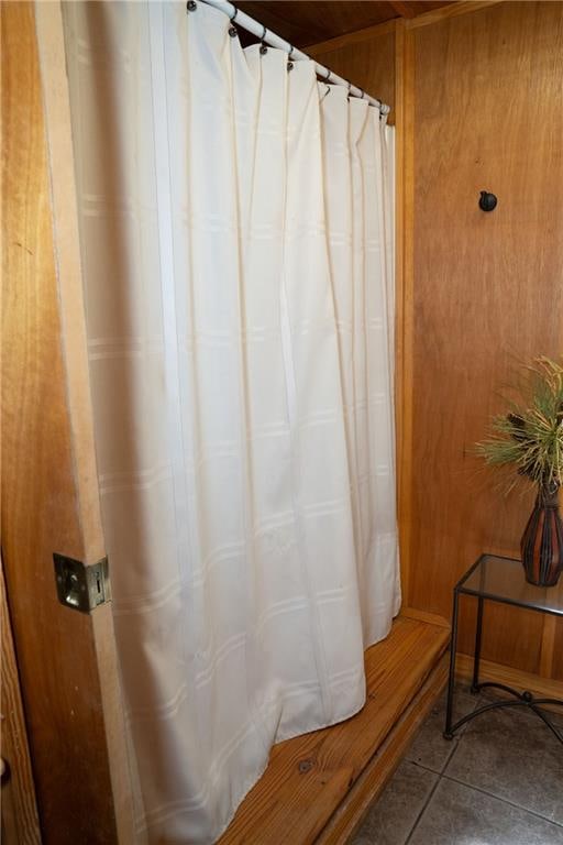 bathroom with wood walls and tile floors