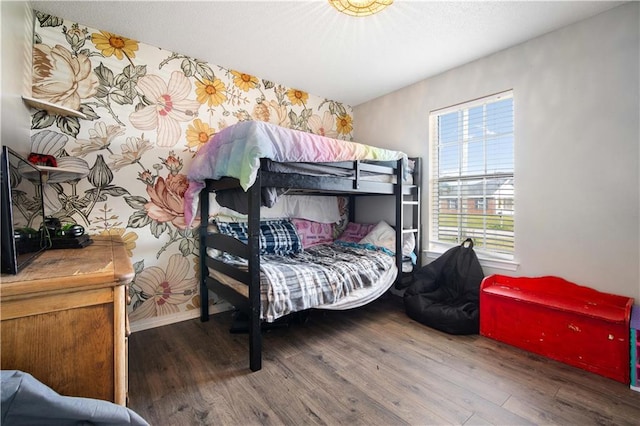 bedroom featuring wallpapered walls, baseboards, and wood finished floors