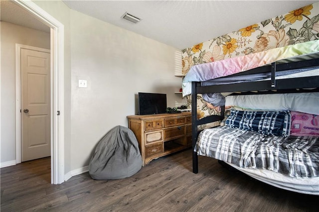 bedroom featuring baseboards, visible vents, and wood finished floors