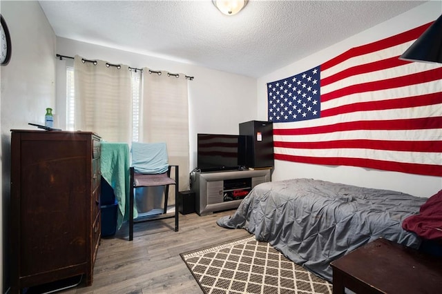 bedroom with a textured ceiling and wood finished floors