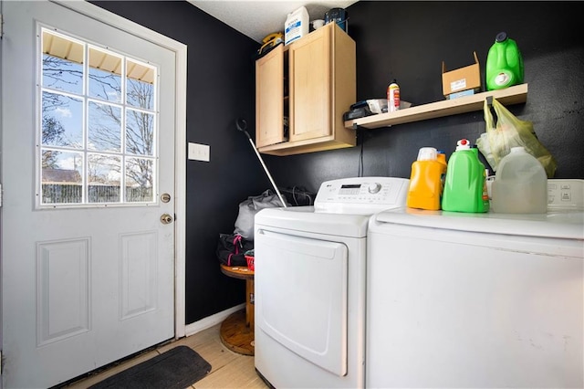 washroom featuring light wood-type flooring, washing machine and dryer, cabinet space, and baseboards