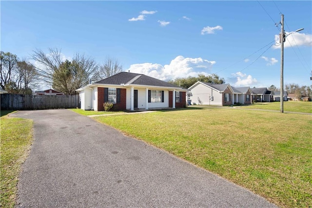 ranch-style home featuring a front yard, brick siding, fence, and driveway