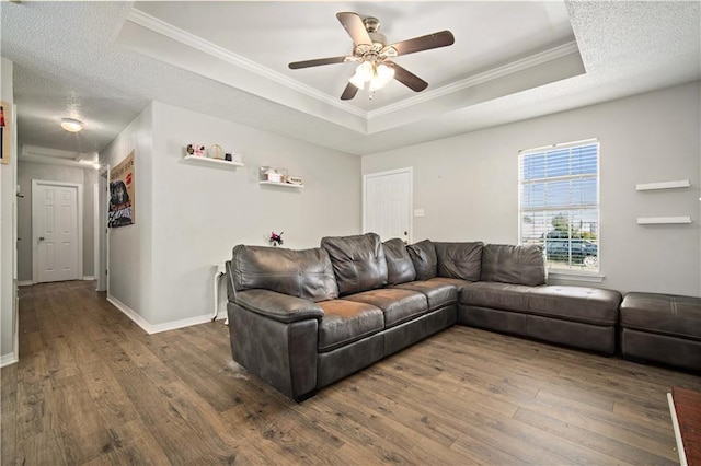 living area featuring ornamental molding, a tray ceiling, and wood finished floors