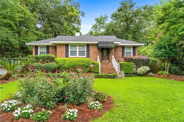 ranch-style home with a front yard, brick siding, a chimney, and roof with shingles