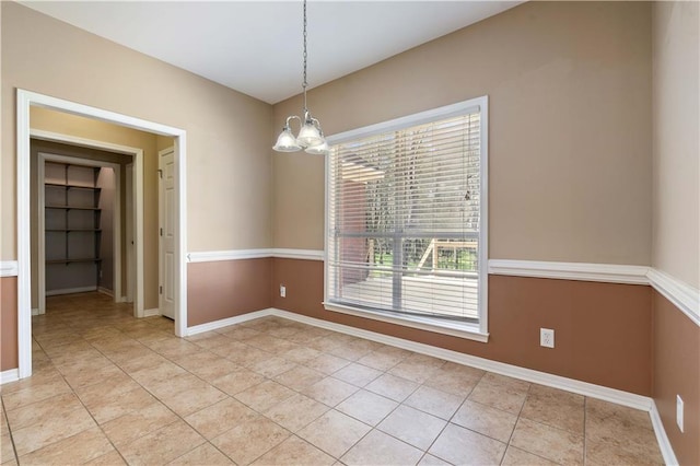 empty room with light tile patterned flooring and a chandelier