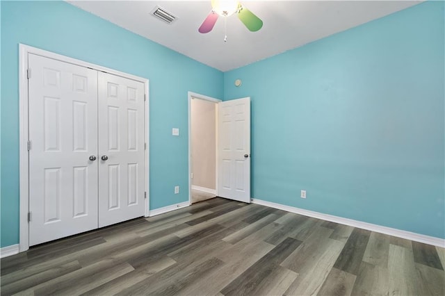 unfurnished bedroom featuring ceiling fan, a closet, and dark wood-type flooring