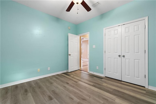 unfurnished bedroom with ceiling fan, wood-type flooring, and a closet