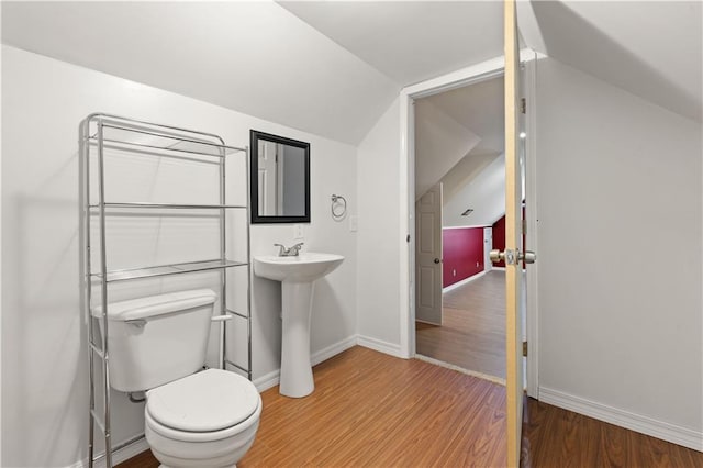 bathroom with toilet, vaulted ceiling, and wood-type flooring