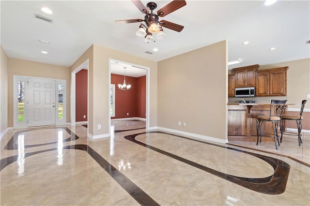 foyer entrance with ceiling fan with notable chandelier