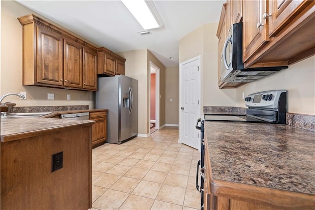 kitchen with appliances with stainless steel finishes, sink, and light tile patterned floors