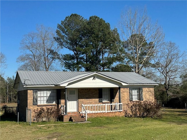 view of front facade with covered porch, brick siding, metal roof, and a front lawn