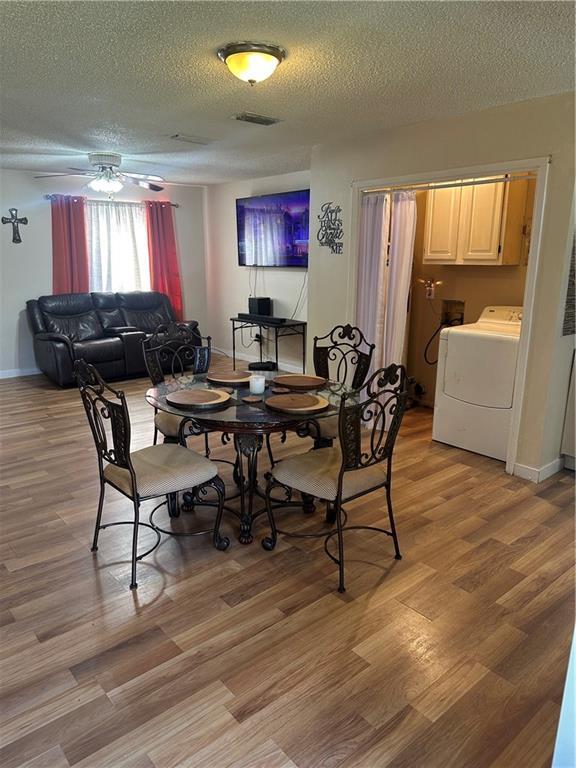 dining room with a textured ceiling, ceiling fan, light wood-style flooring, baseboards, and washer / clothes dryer